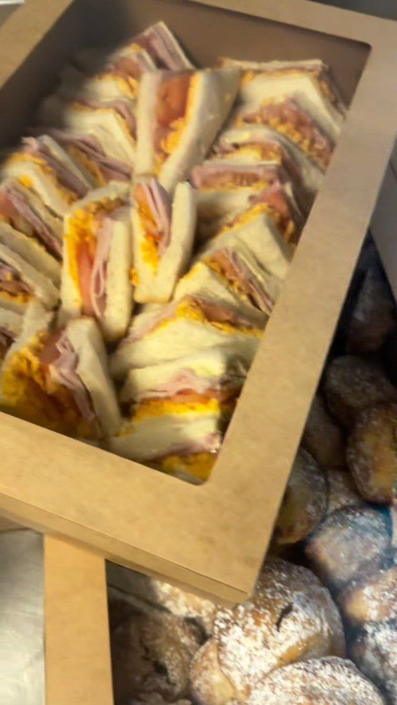 A catering box of ham and cheese sandwiches